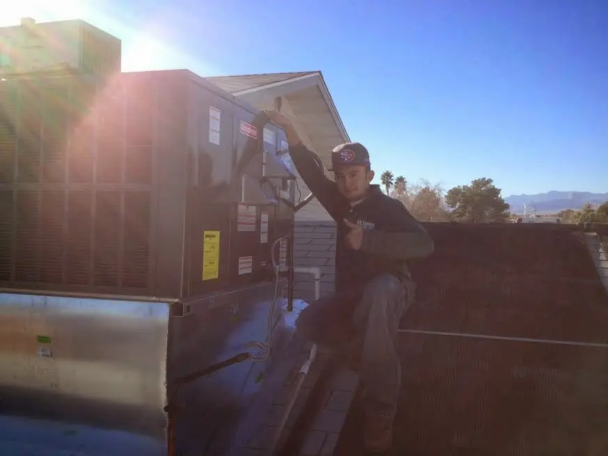 HVAC technician performing AC Tune-Up on a rooftop unit in River Falls